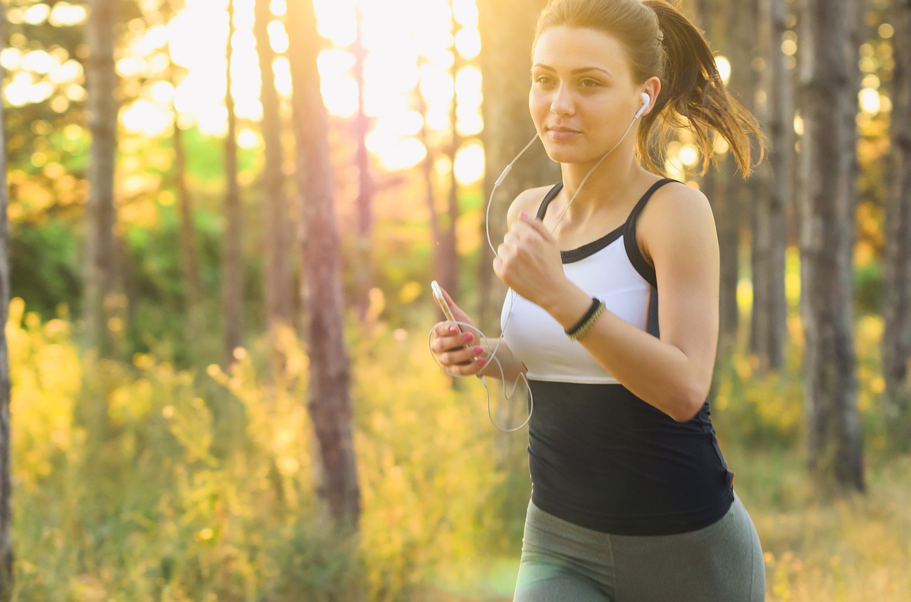 イヤホンで音楽を聴きながらジョギングする女性の写真