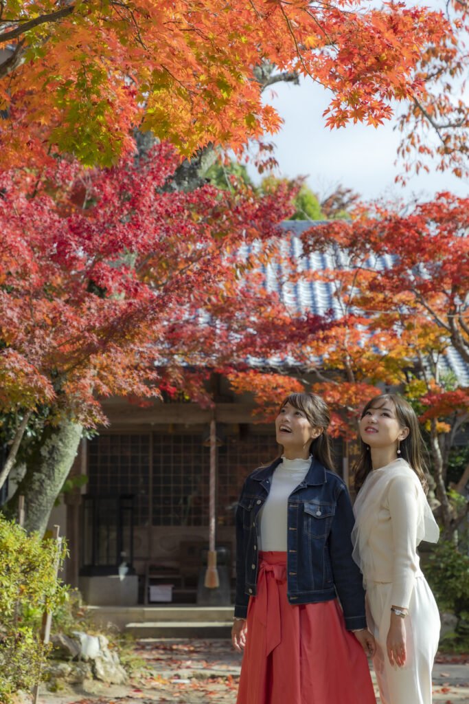 女性が二人、楽しそうに紅葉を見上げている。
