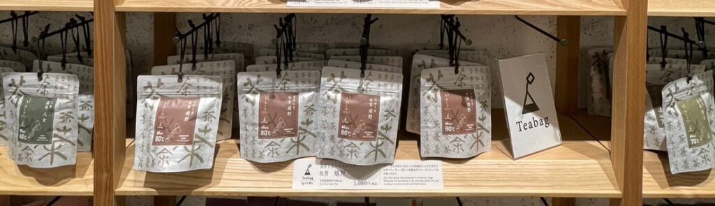 「日本茶きみくら」店内商品の棚をアップで撮影した写真。「茶」という漢字の筆文字が模様のように書かれたパッケージのお茶。