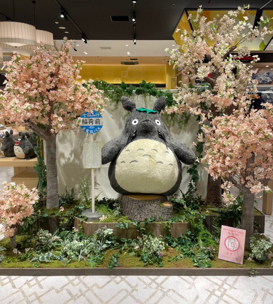日本を代表するアニメ制作会社「スタジオジブリ」の作品「となりのトトロ」のキャラクター「トトロ」の大きなぬいぐるみと記念写真がとれるフォトスポット。桜の造花に囲まれている。