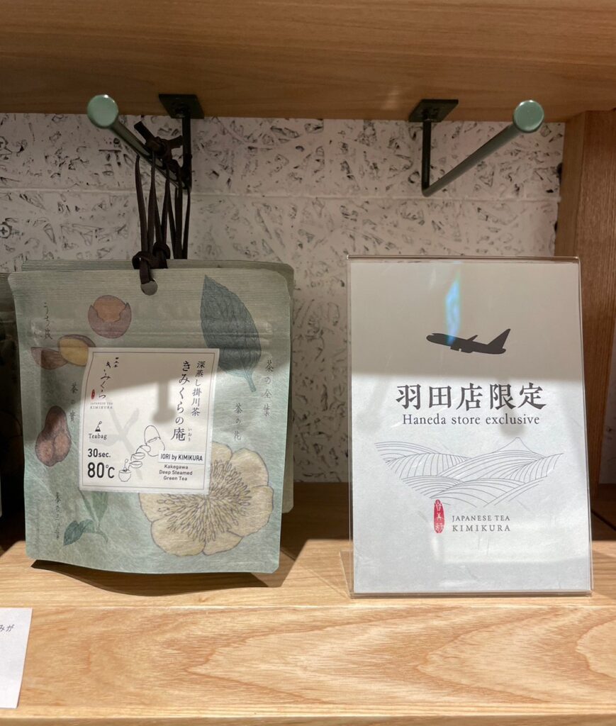 「日本茶きみくら」の商品「Art Print Package (Teabag) Collection」の1つ、羽田店限定の「深蒸し掛川茶 きみくらの庵」。緑系のパッケージでお茶に関する植物の絵がデザインされている。